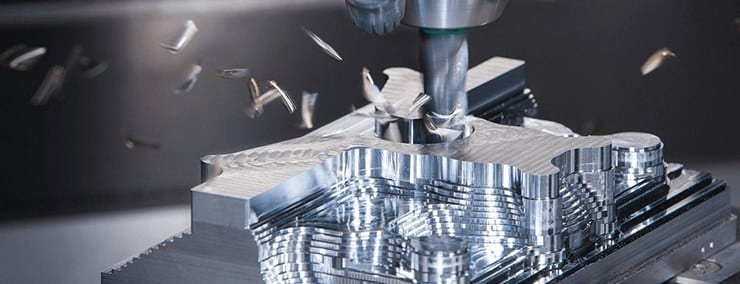 A CNC milling machine cutting a metal part, with metal shavings flying off the tool